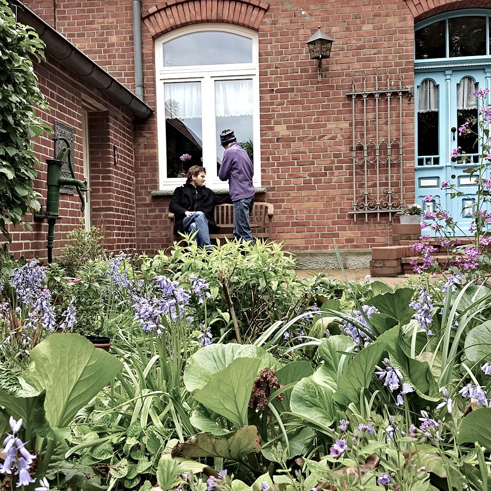 Ausschnitt eines verklinkertes Wohnhaus Blumenbetten und Familienmitgliedern